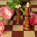 Pink flowers on a chess board next to chess pieces