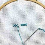 Cross stitch in hoop with several blue stitches in a row