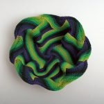 Wavy circle of green and blue fibers woven together