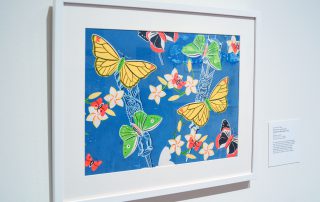 Framed print of butterflies in yellow, green, and red/black on a blue background