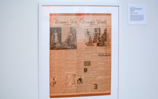 Framed newspaper clippings of an article titled Women's World with pictures of women in Aloha themed dresses