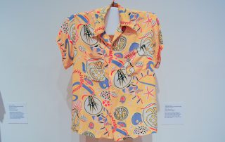 An Aloha shirt with white and blue abstract images on a yellow background
