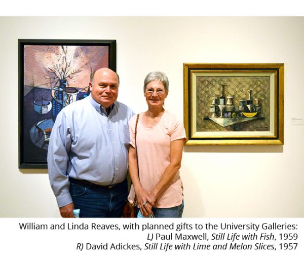 Caption reads: William and Linda Reaves, with planned gifts to the University Galleries: L) Paul Maxwell, Still Life with Fish, 1959 R)David Adickes, Still Life with Lime and Melon Slices, 1957. Color photograph. William "Bill" and Linda Reaves stand next to each other. He has on a blue button down shirt and blue jeans. She is wearing a light pink top and blue jeans. They are standing in front of two modern paintings they donated to the galleries. Both are still life paintings of tabletops and various items.