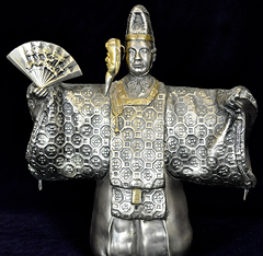 Brass, male Japanese theatre figure in an elaborate layered winter kimono with gold mask and fan. Mask is hinged to 'open' and reveal the actor's face.