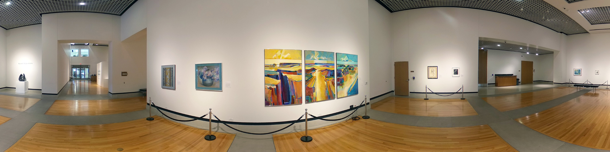 360 degree view of the interior of an art gallery. Colorful paintings hang on the wall at a distance and there is a sculpture on a pedestal on the far left.