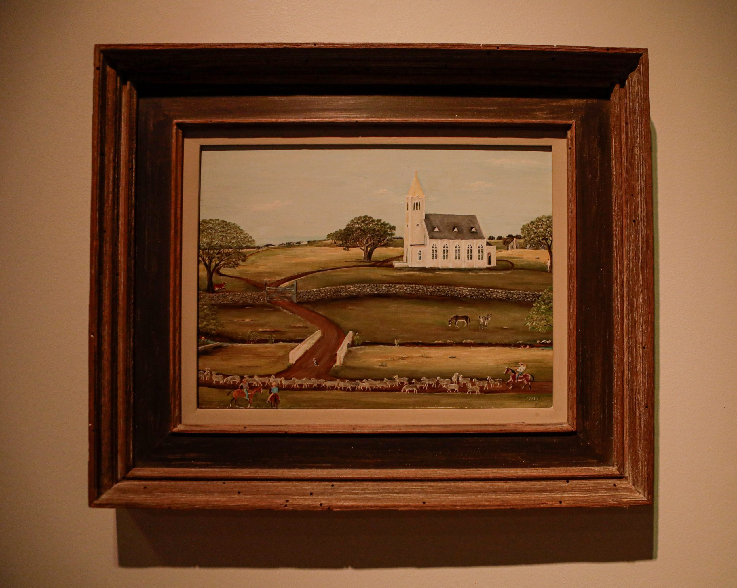Primitive painting of a white church in the countryside. This image shows the painting as it would look under gas lighting.