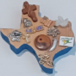 Wooden block cut in the shape of Texas adorned with small religious trinkets.