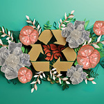 Cardboard recyle symbol surrounded by flowers made of paper, water bottles and bubble wrap