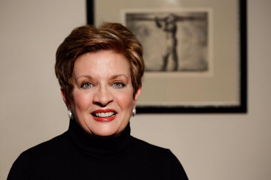 Headshot of Sheryl Fiegel standing in front of an art print in the background.